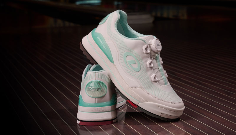 The women's SST X bowling shoe in White/Seaglass (white and teal) on a brown wood floor.